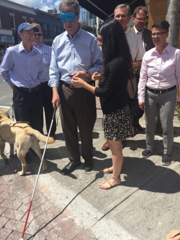 The mayor of Ottawa at an intersection trying out the Key2Access technology while wearing a blindfold.